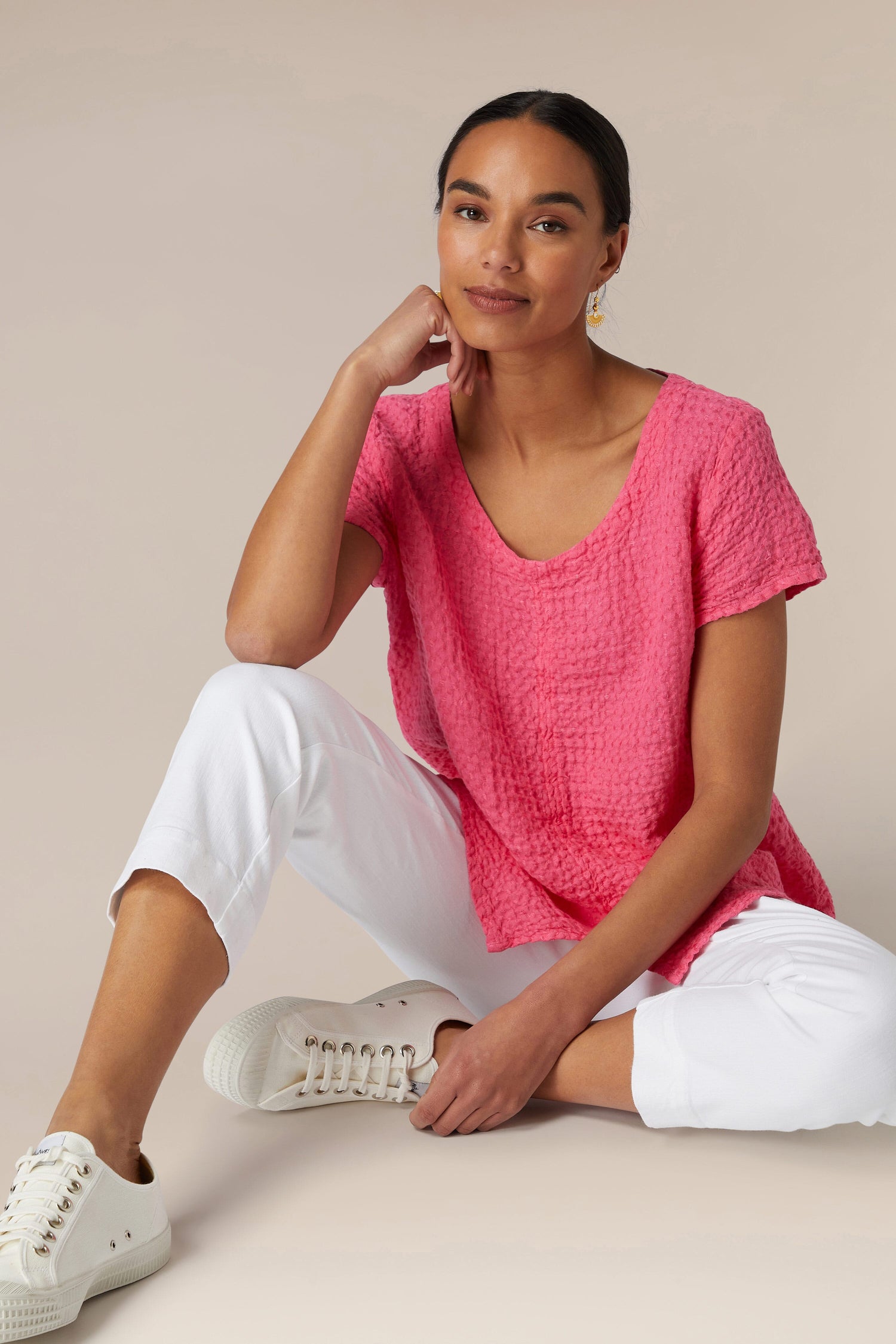 Woman in a pink top and Stretch Cotton Slim Trousers sitting casually against a neutral background.