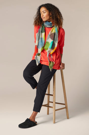 A woman is sitting on a stool wearing Stretch Cotton Slim Trousers, showcasing her timeless style.