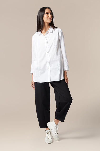 An elegant woman wearing a Paper Cotton Shirt and black trousers.