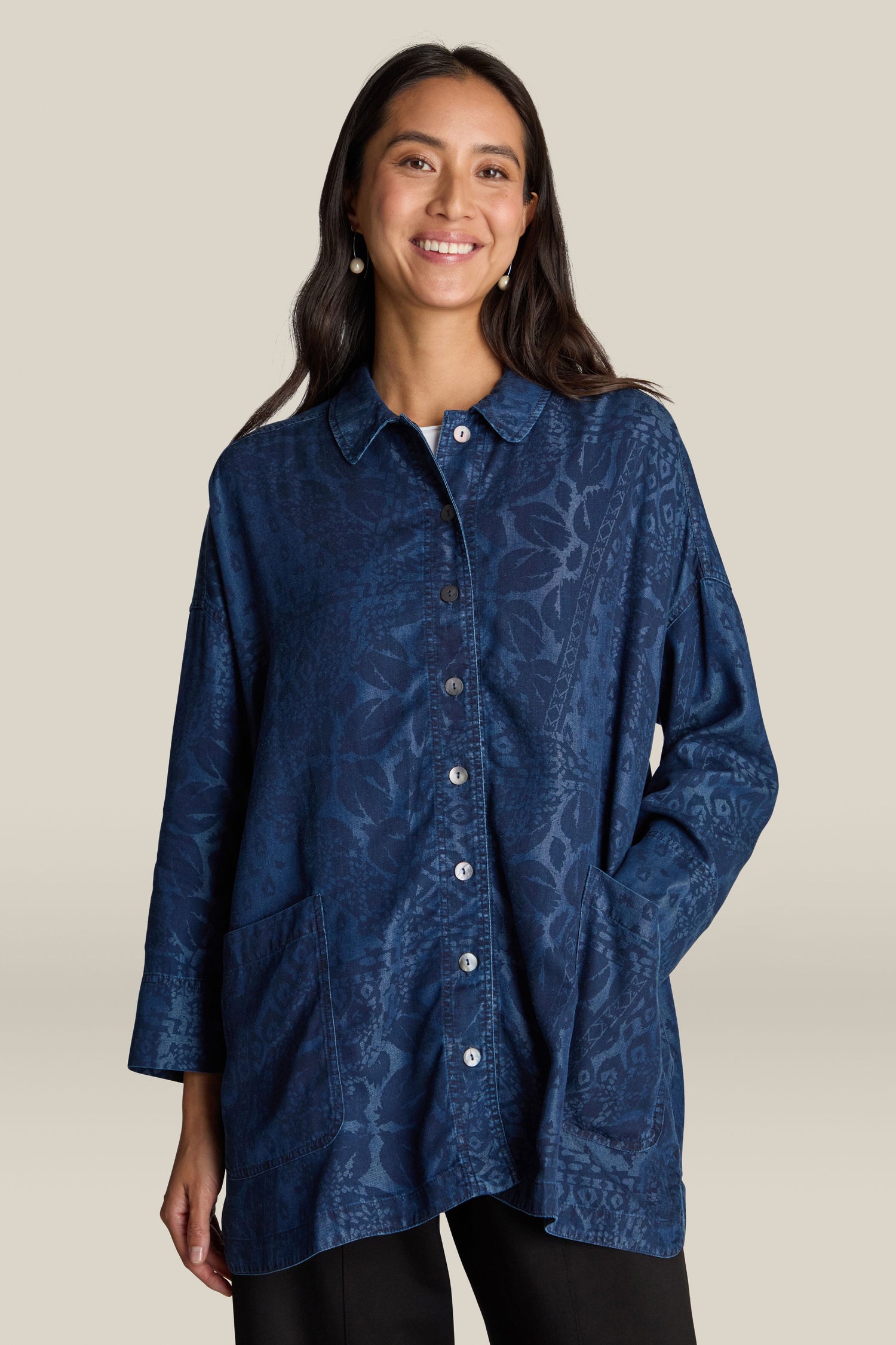 Person wearing the Abstract Patchwork Print Shirt, a navy blue patterned fashion piece with front pockets, smiling against a light beige background.