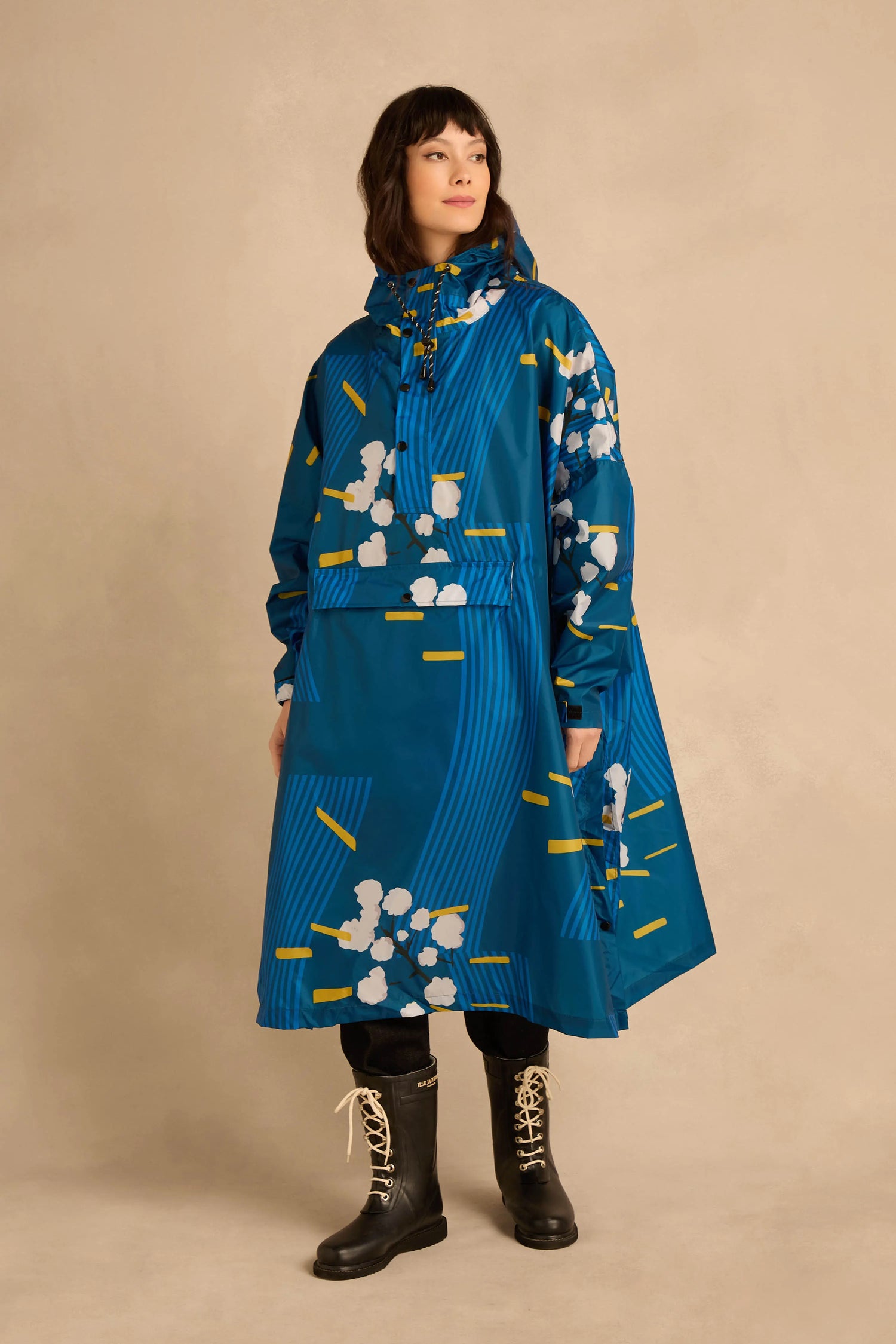 Person wearing a Japanese Blue Blossom Poncho featuring a white blossom and yellow dash pattern, paired with black boots.