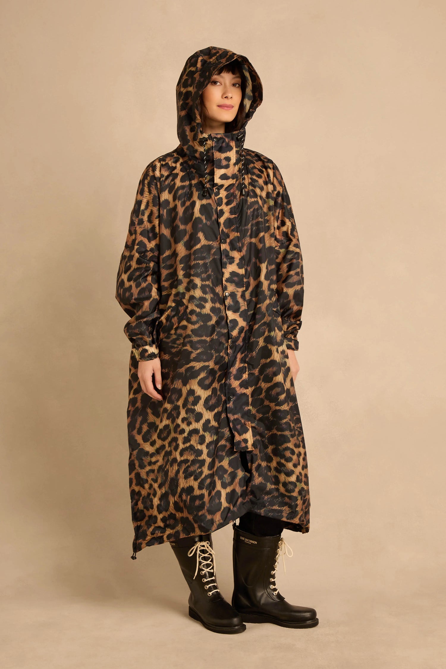 A person wearing an oversized Dark Leopard Rain Coat and black mid-calf boots.