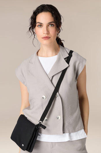 A woman wearing a grey top and pants with a lightweight Recycled Carnaby Crossbody Bag.