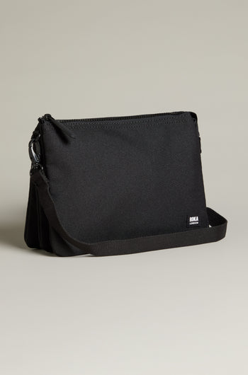 Introducing the Recycled Carnaby Crossbody Bag, a sleek black crossbody crafted from eco-friendly materials. It boasts a minimalist design with a main zipper compartment, an adjustable strap, and weather-resistant properties for all your adventures.