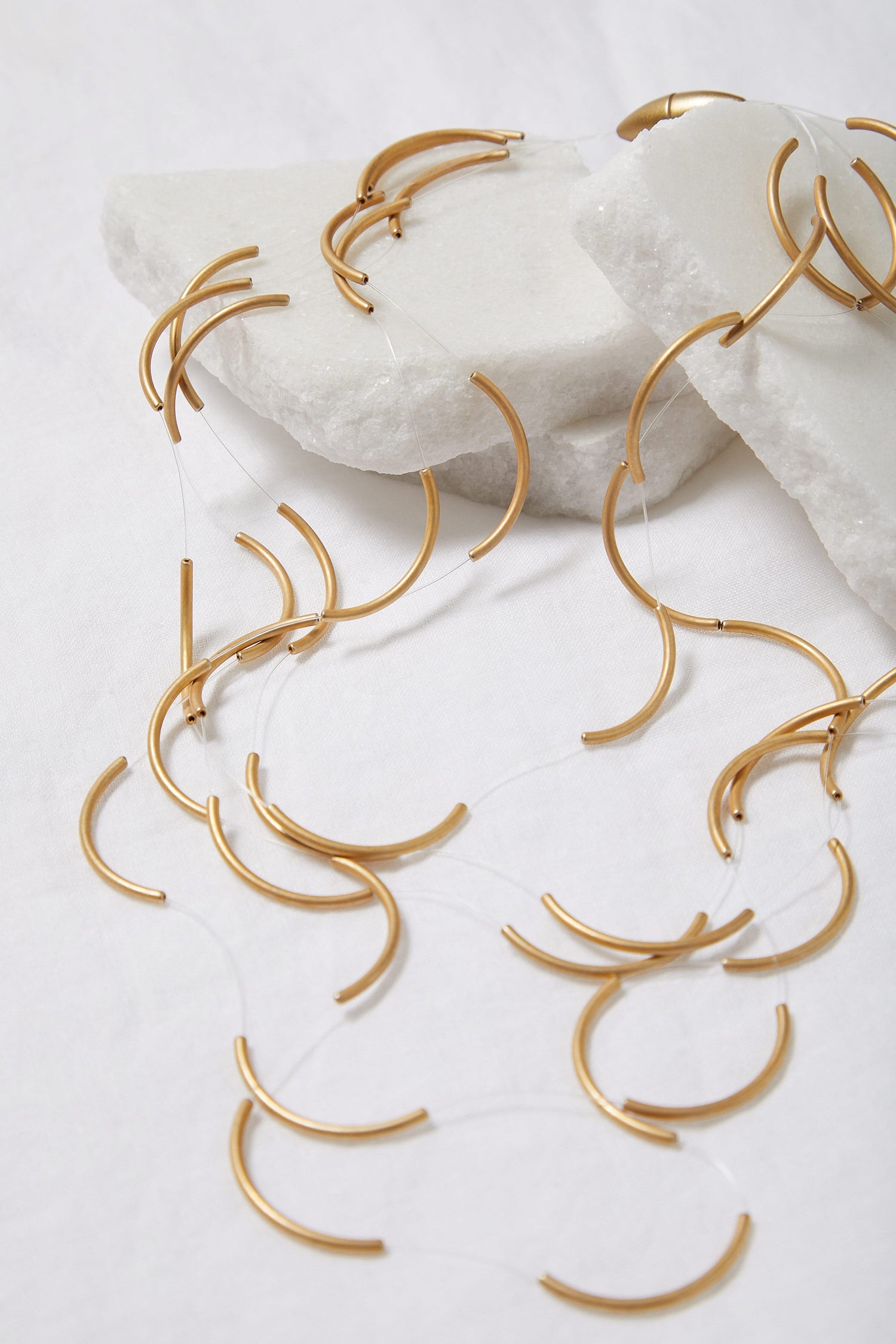 A collection of the Moon Necklace gold plated necklaces laying on top of a white surface.