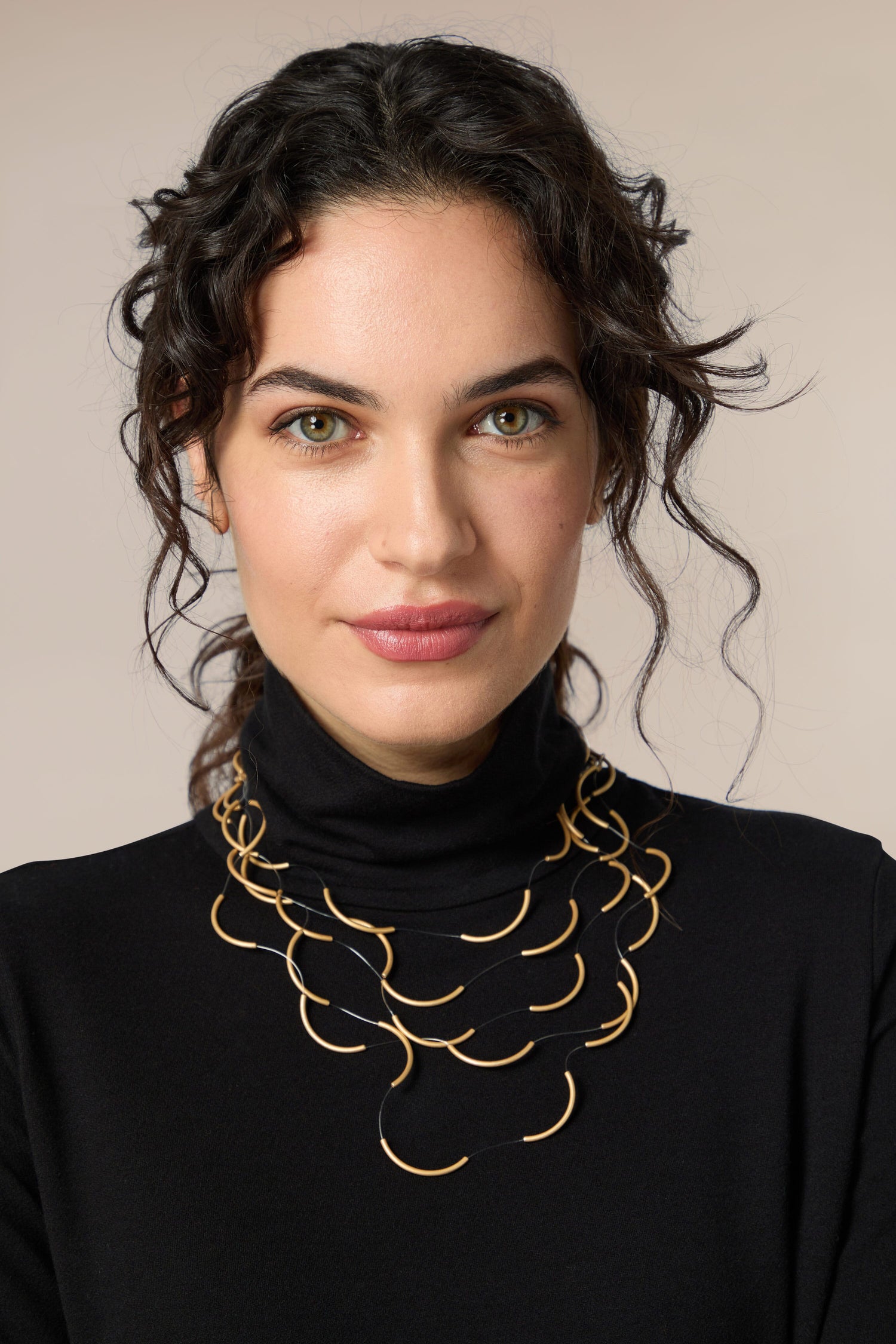 A woman wearing a black turtleneck and gold Crescent Moons necklace.