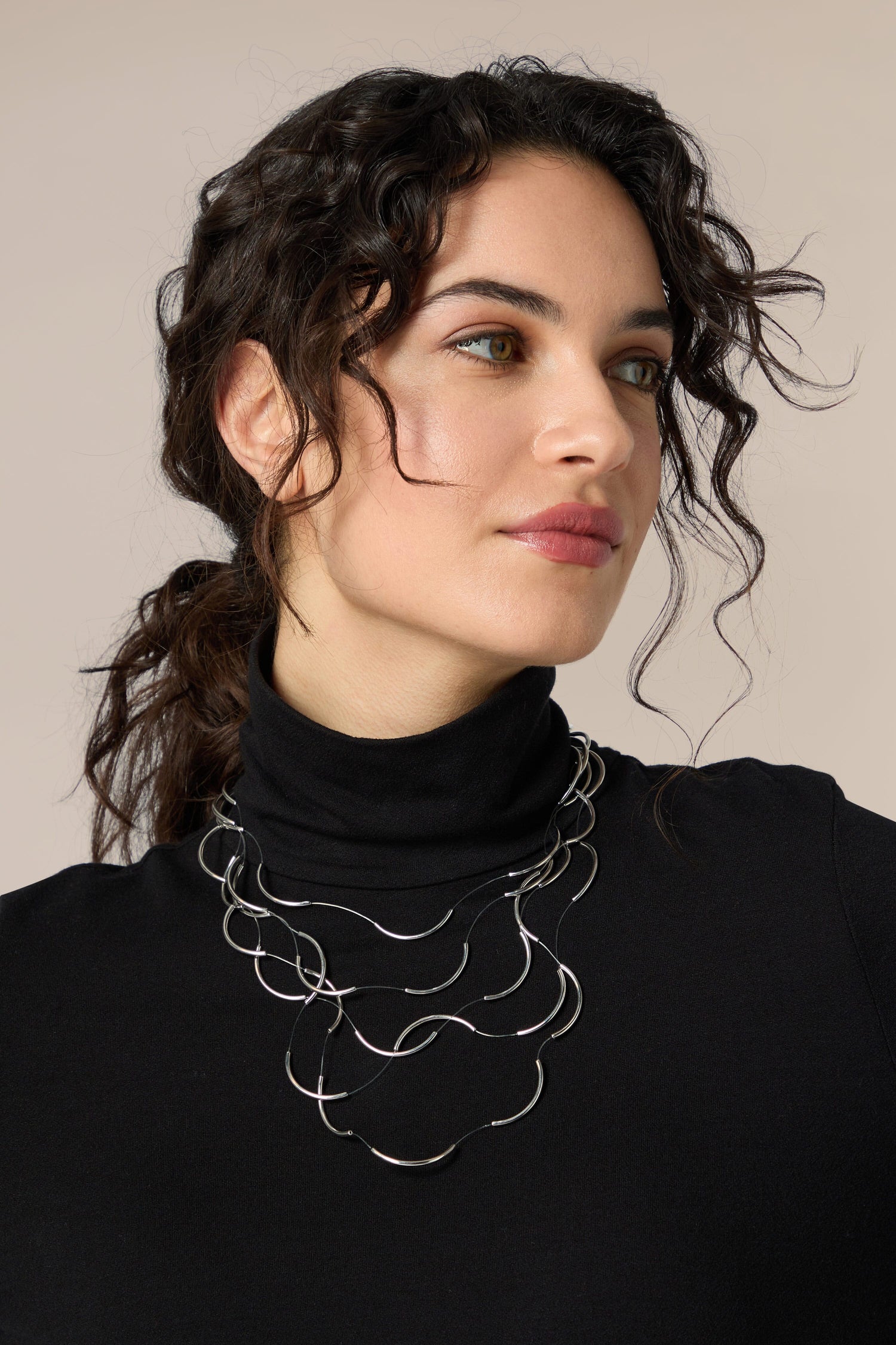 An elegant woman in a black turtleneck is wearing a silver Crescent Moons Necklace.