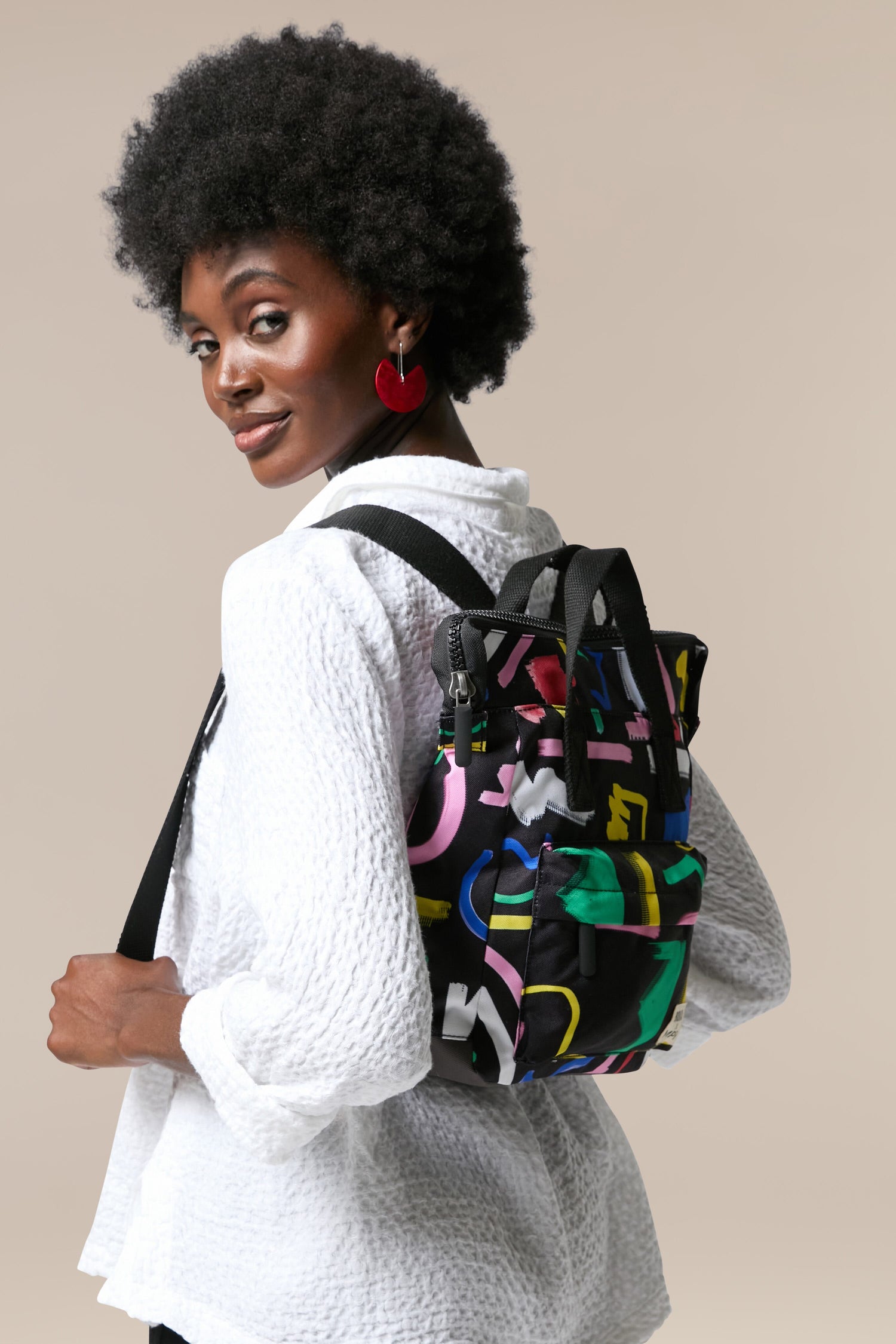 A black woman sporting a Recycled Scribble Print Bantry Bag made of recycled bottles.