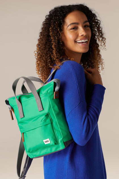 A young woman wearing a weather-resistant green Recycled Bantry Bag made from recycled nylon.