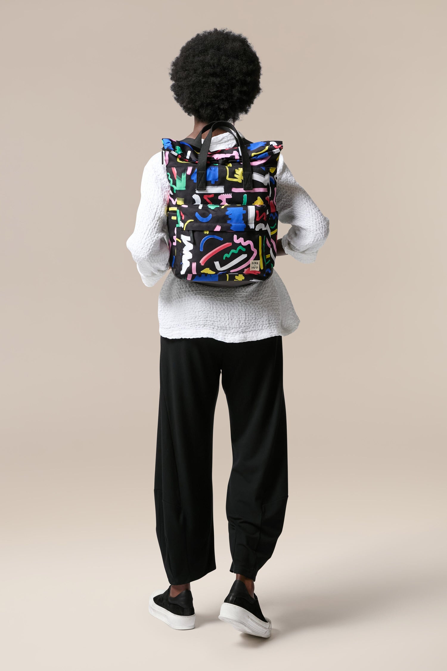 The back of a woman wearing a colorful Recycled Canfield Scribble Print Bag made from recycled bottles.