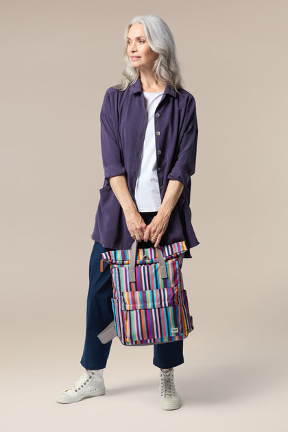 A woman holding a Recycled Canvas Canfield Bag with a colorful roll-top design.