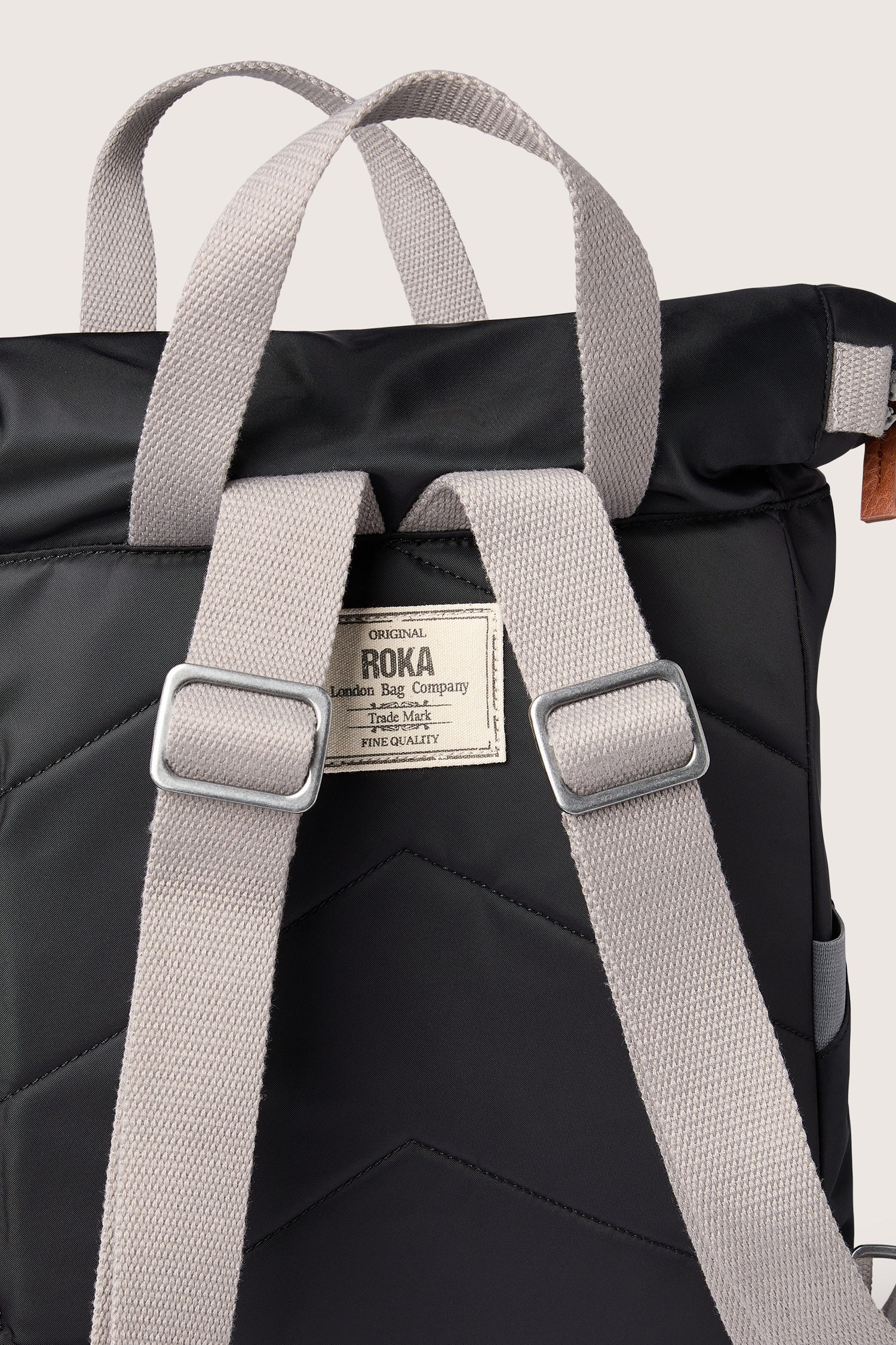 A Recycled Canfield Bag, a weather-resistant backpack with storage space, featuring black color, grey straps, and buckles.