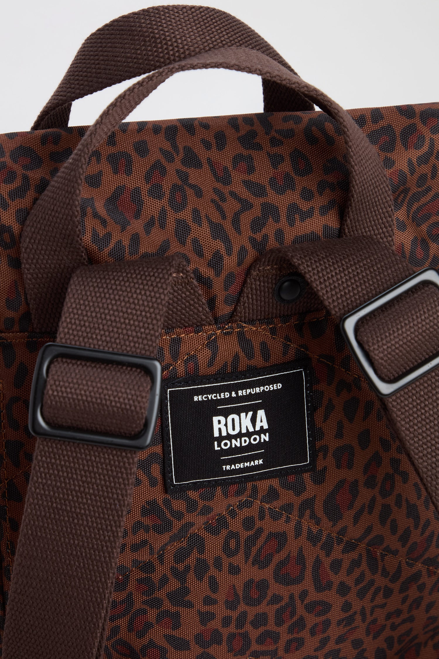 Close-up of the Mini Leopard Canfield Canvas Bag, crafted from recycled canvas with a stylish leopard print, featuring a ROKA London label and two adjustable straps.