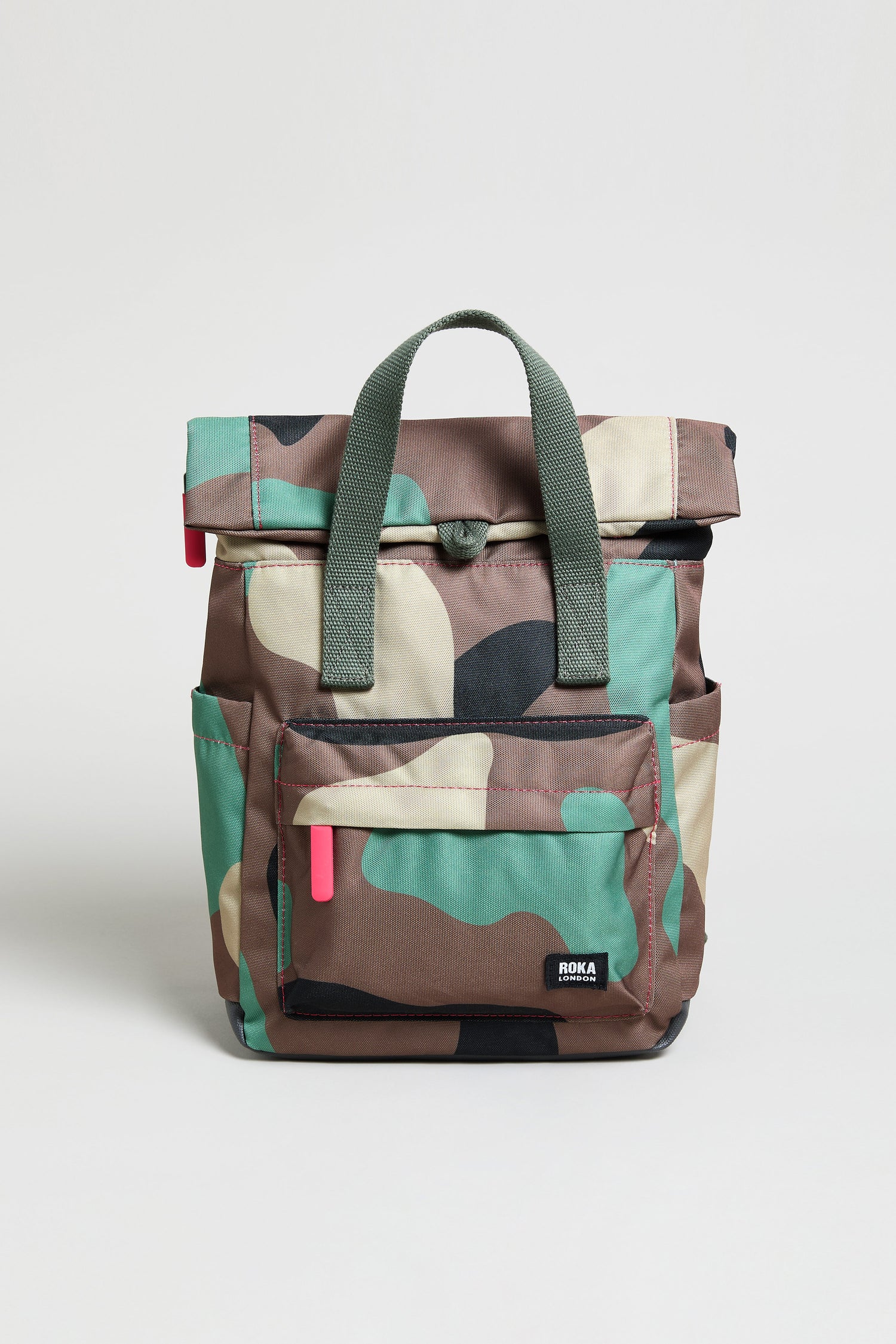 The Recycled Canvas Canfield Bag is a water-repellent backpack with a camouflage pattern, green handles, a front pocket, and red zipper pulls. Designed for durability and style. Shown against a plain white background.