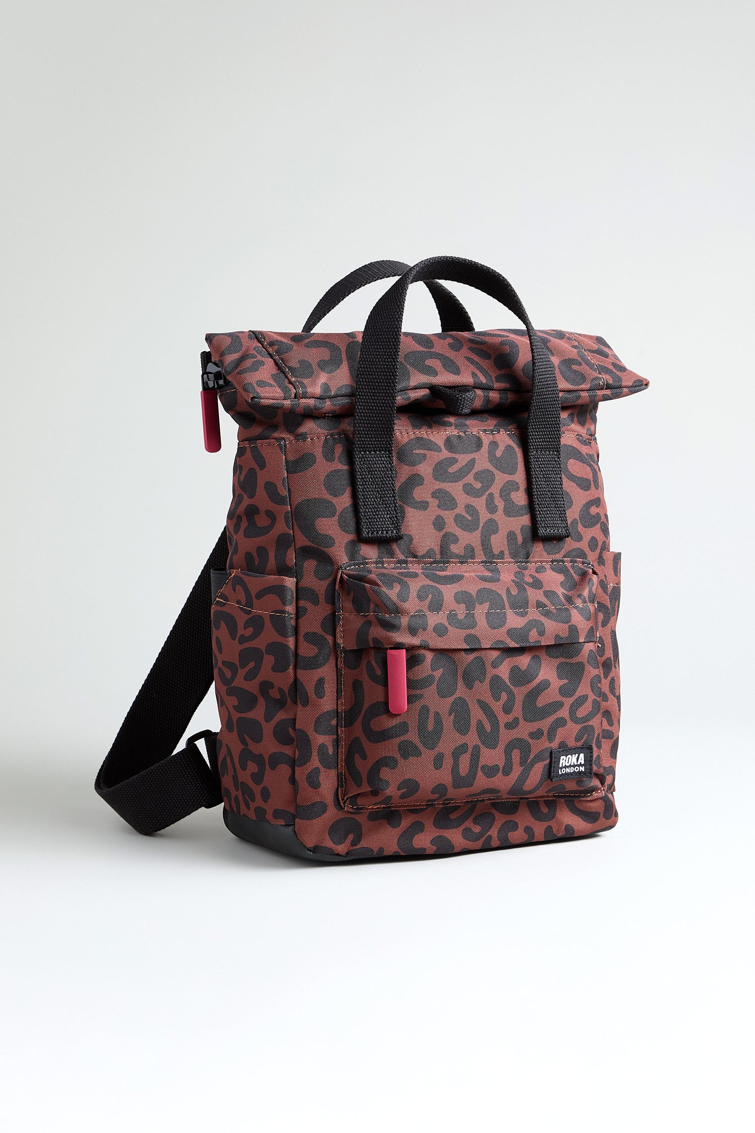 The Recycled Canvas Canfield Leopard Backpack features a stylish leopard print, black straps, a front pocket, red zipper pulls, and water-resistant recycled canvas shown against a plain white background.
