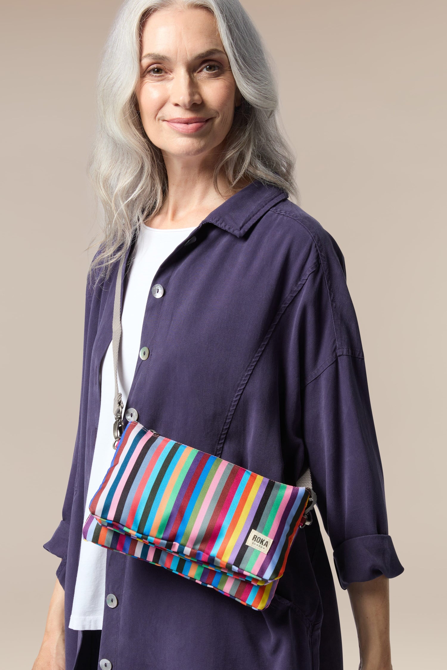 A woman carrying a weather-resistant, Recycled Canvas Carnaby Crossbody Bag.