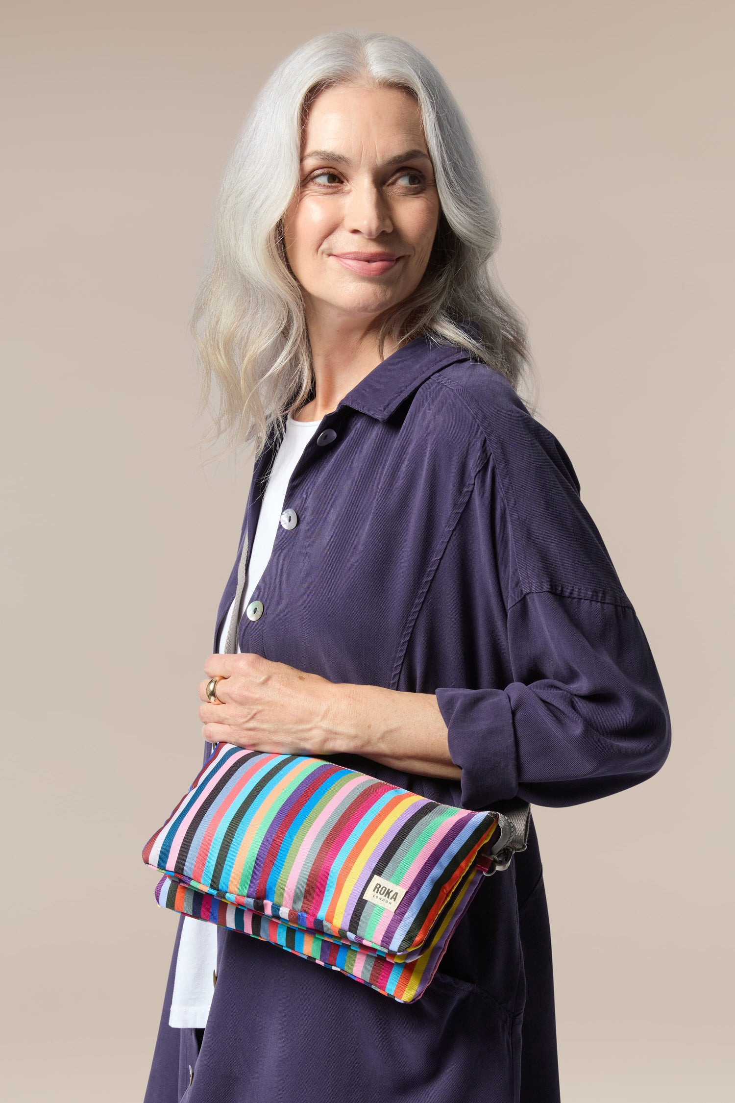 A woman holding a Recycled Canvas Carnaby Crossbody Bag with a detachable strap.