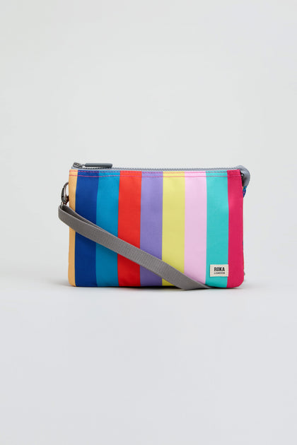 The Wide Multistripe Carnaby Crossbody Canvas Bag, featuring vertical rainbow stripes and a gray strap, is crafted from weather-resistant recycled canvas and is displayed on a plain light background.