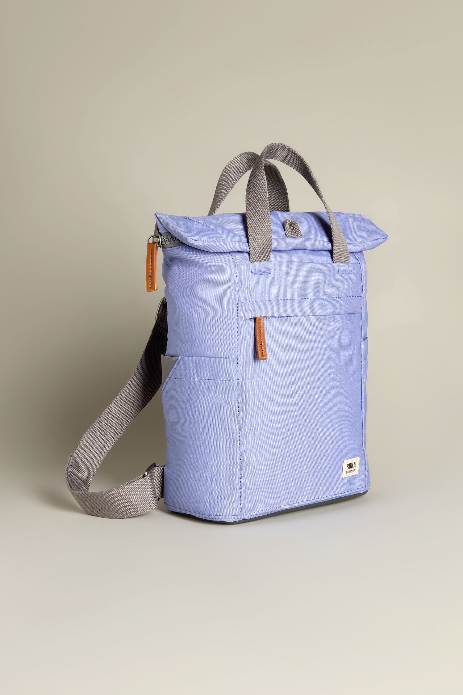 The Recycled Canvas Small Finchley Bag, in blue with gray straps and two brown leather zipper pulls, stands against a plain background, highlighting its eco-conscious design.