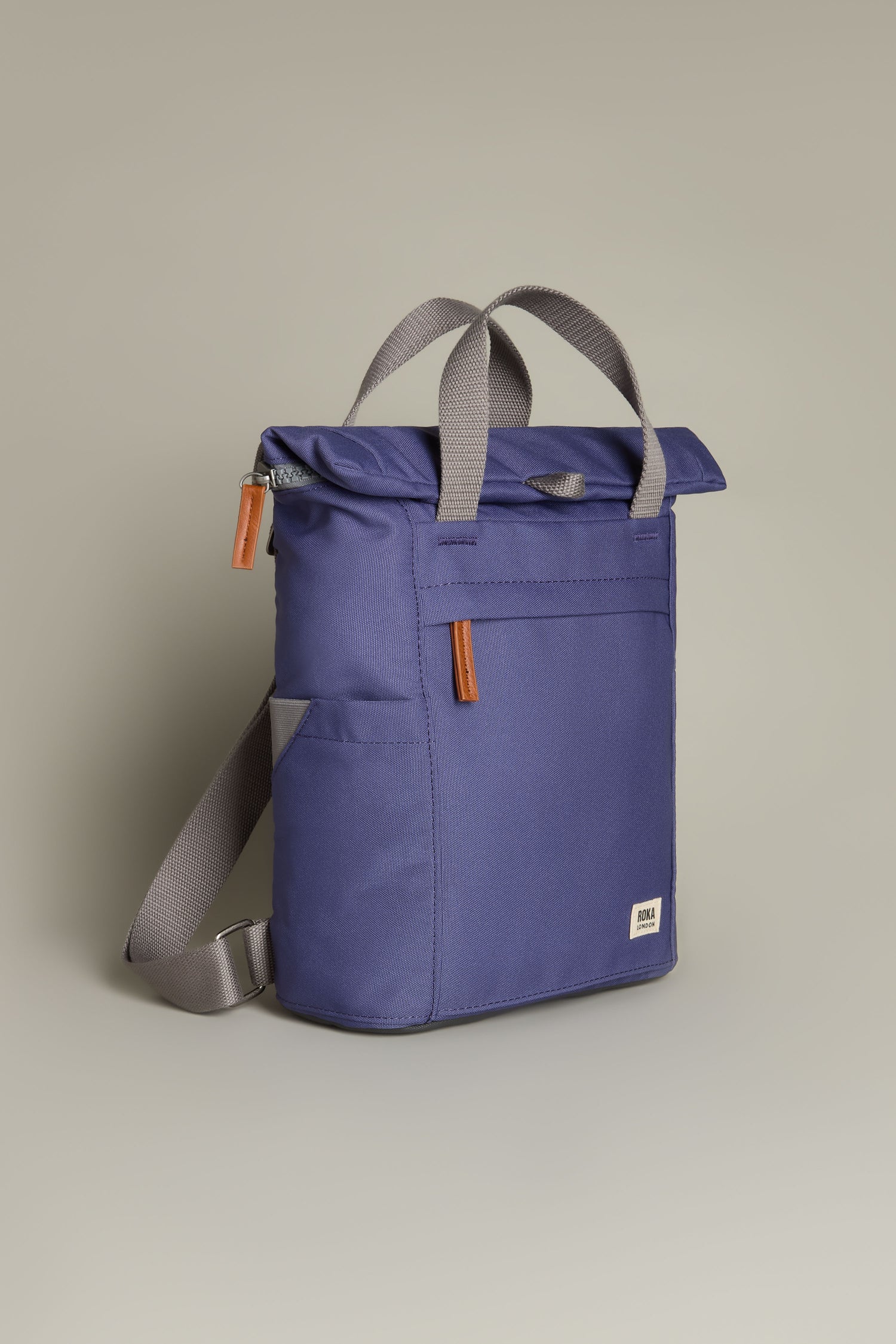 The Recycled Canvas Small Finchley Bag, in blue with gray straps and two brown leather zipper pulls, stands against a plain background, highlighting its eco-conscious design.