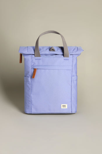 The Recycled Canvas Small Finchley Bag in light purple has a roll-top closure, two handles, a front pocket, and a logo patch at the bottom. Enjoy eco-conscious design with this stylish sustainable backpack ideal for everyday adventures.