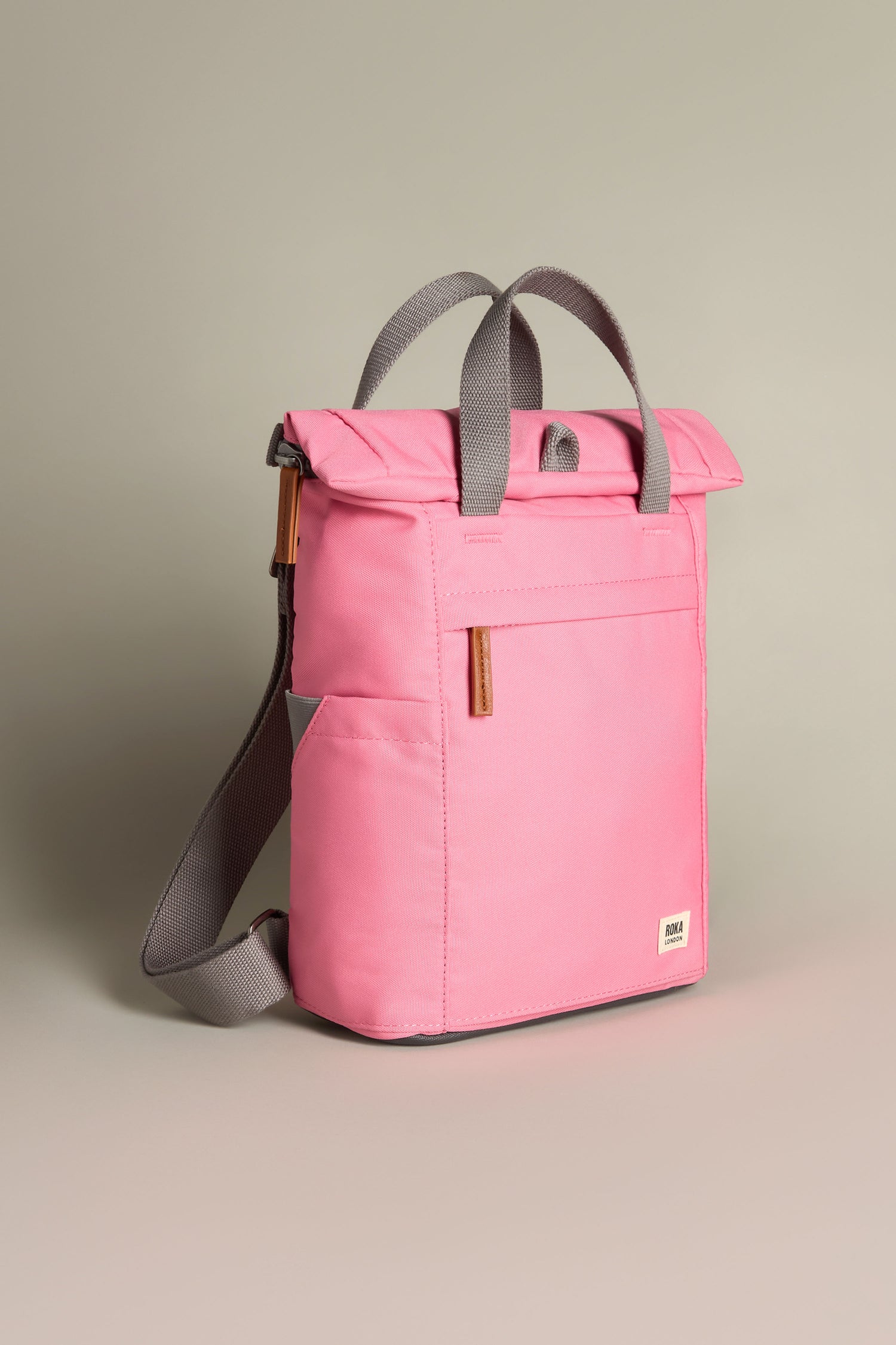 The Recycled Canvas Small Finchley Bag is a pink tote with gray handles, shoulder strap, roll-top closure, and front pocket, crafted from recycled canvas for eco-conscious appeal.