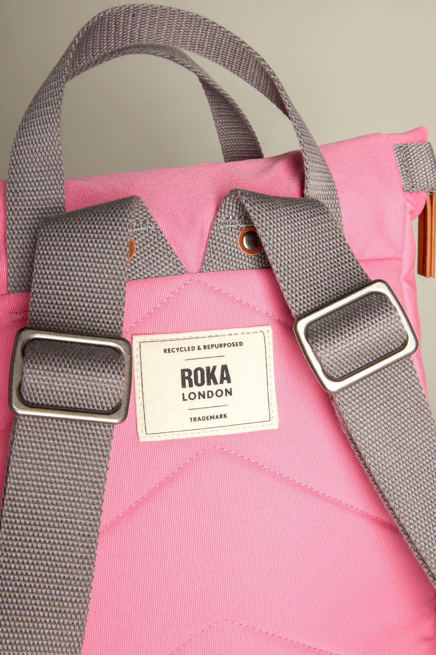 Close-up of the Recycled Canvas Small Finchley Bag, featuring pink canvas with gray straps and a "Roka London" label, highlighting its eco-conscious design.