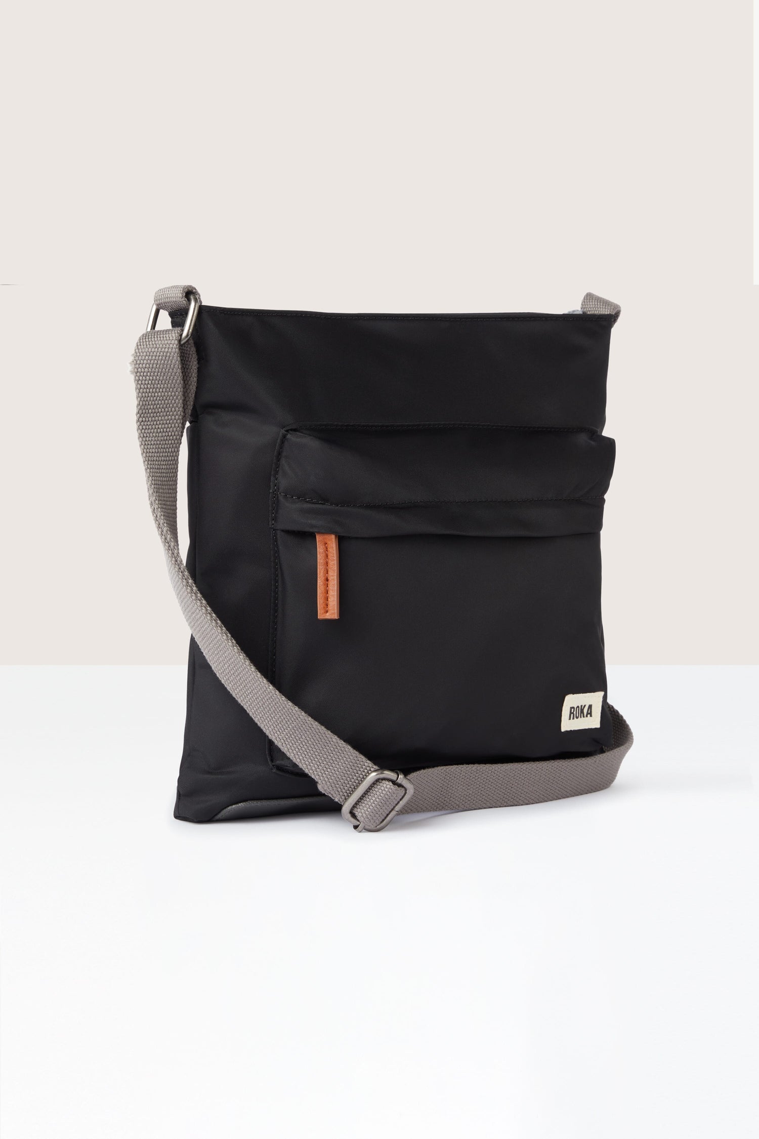 A sleek black Kennington Crossbody Bag with an adjustable grey strap.