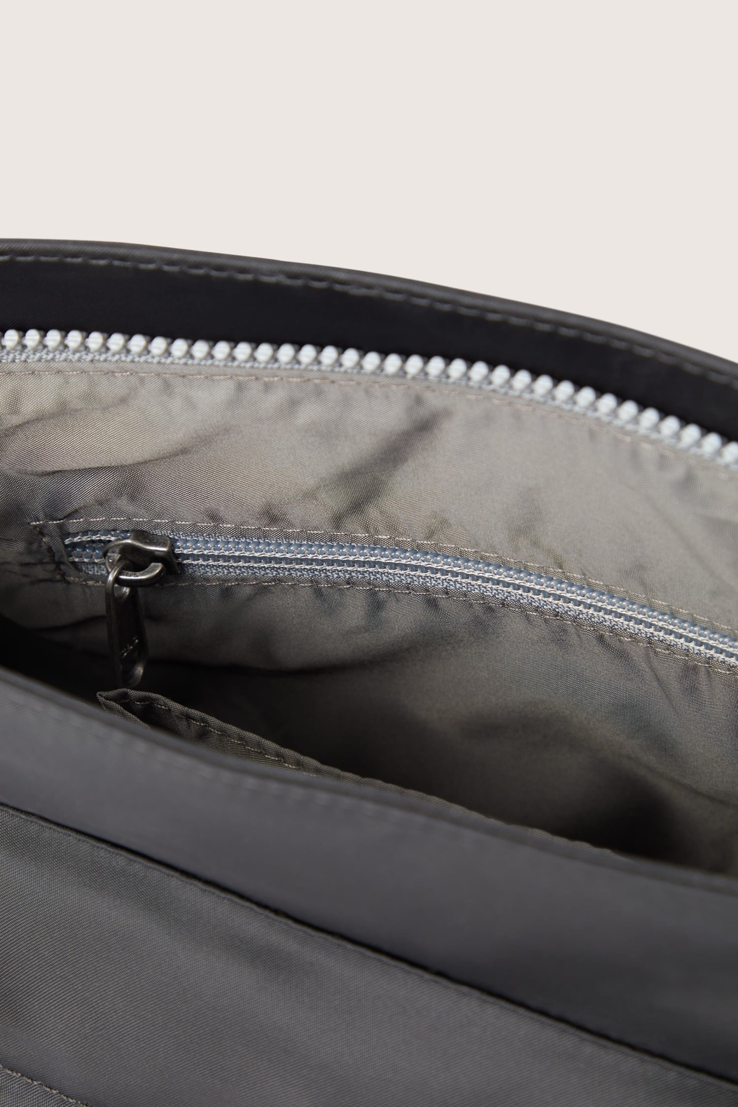 The inside of a Kennington Crossbody Bag with adjustable straps and zippers.