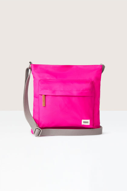 A sleek pink Kennington Crossbody Bag with an adjustable strap on a white background.