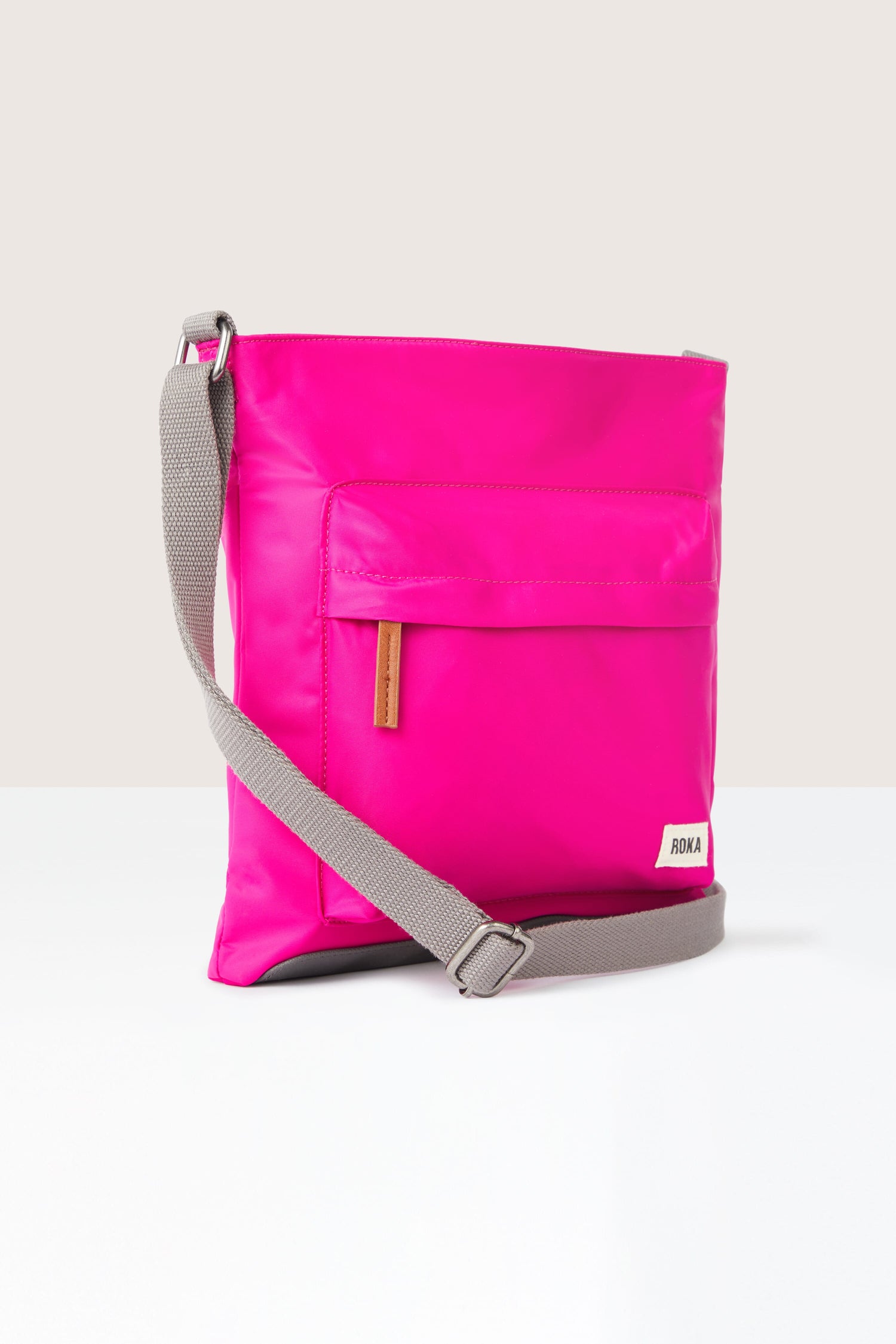 A sleek pink Kennington Crossbody Bag with an adjustable strap.