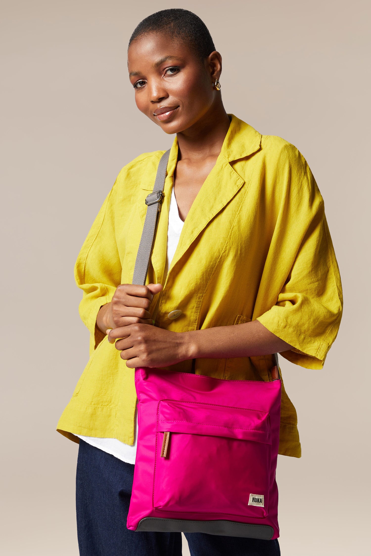 A woman with a sleek yellow jacket and Kennington Crossbody Bag.