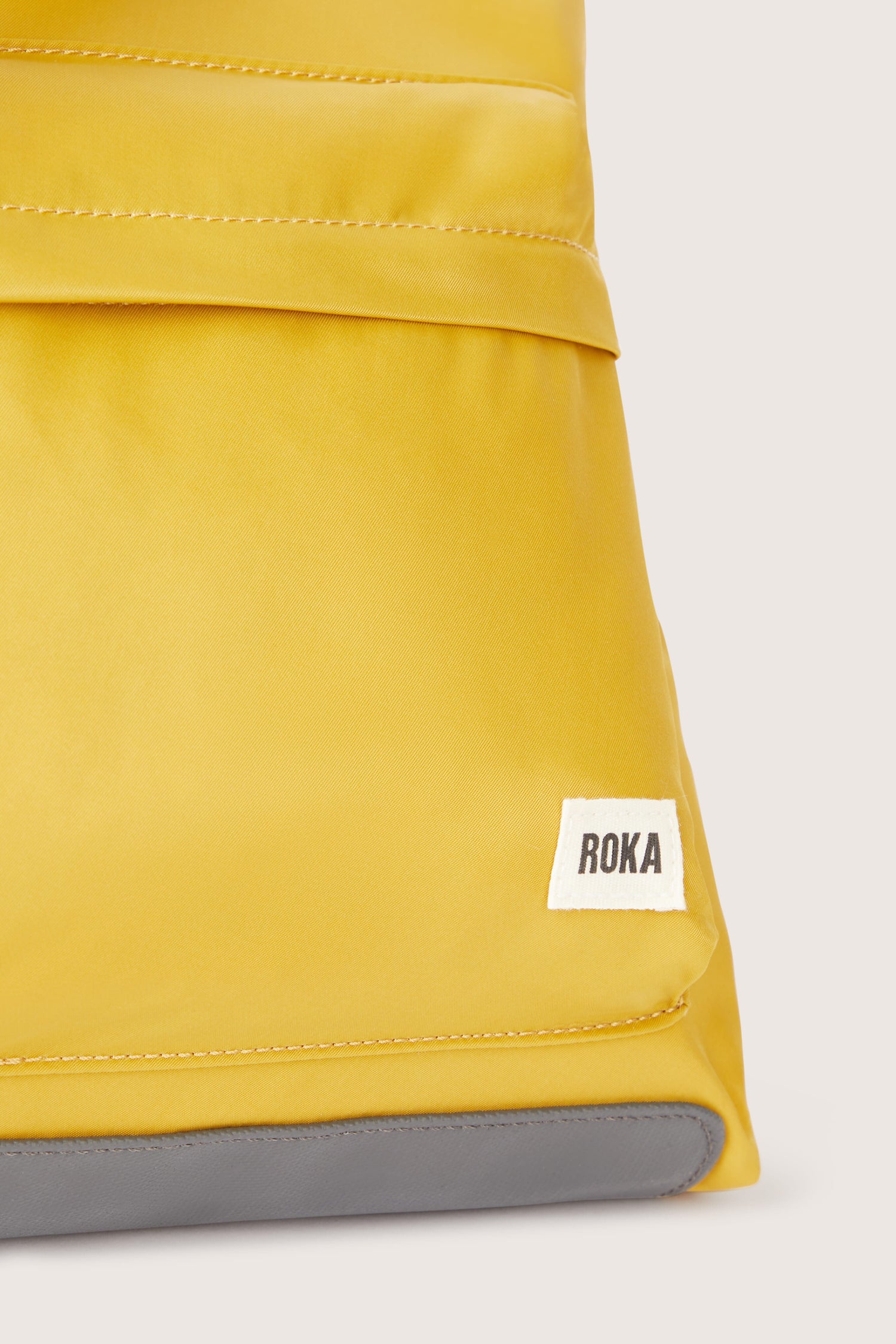 A sleek yellow Kennington Crossbody Bag with the word ruka on it.