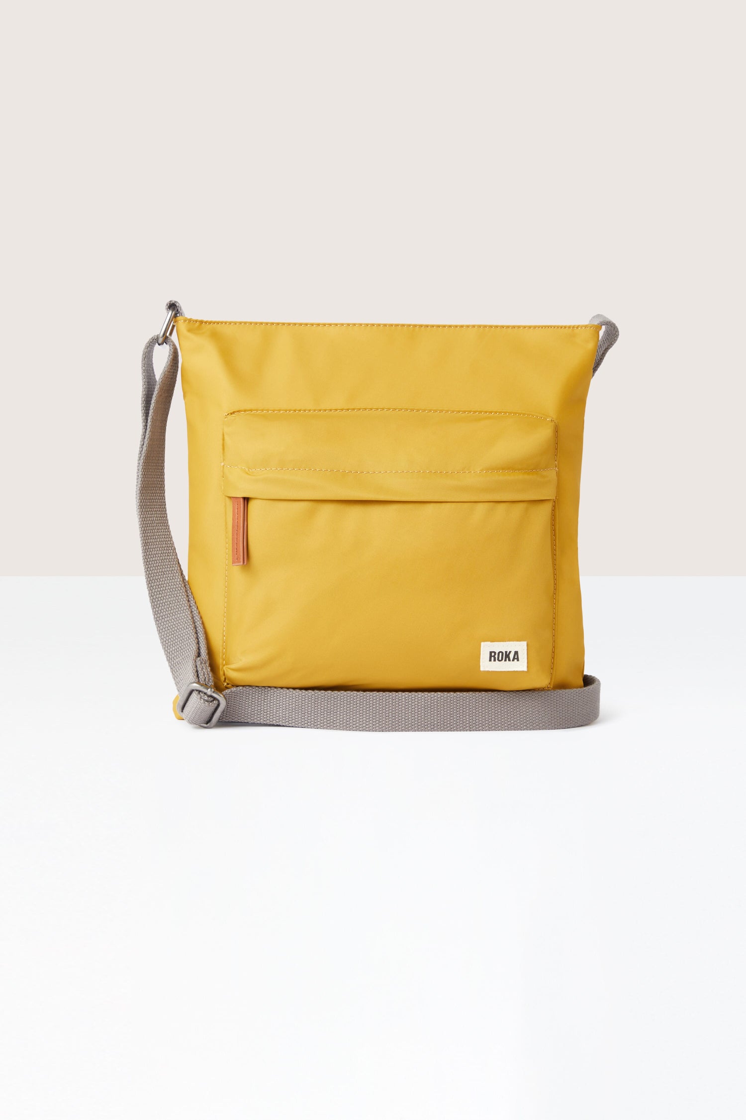 A sleek yellow Kennington Crossbody Bag with an adjustable strap on a white background.