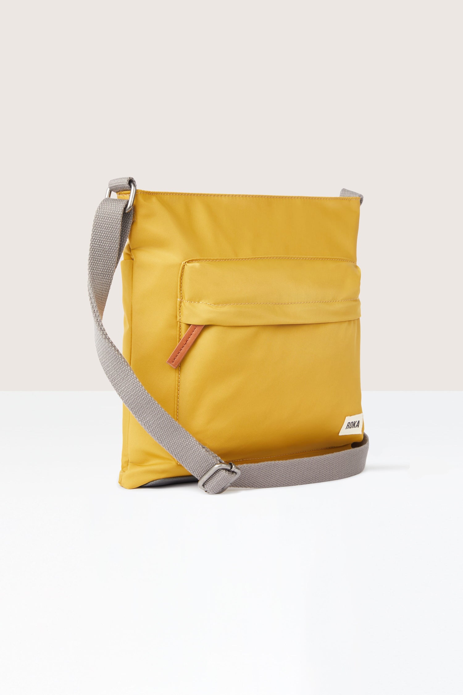 A sleek yellow Kennington Crossbody Bag with an adjustable strap on a white background.