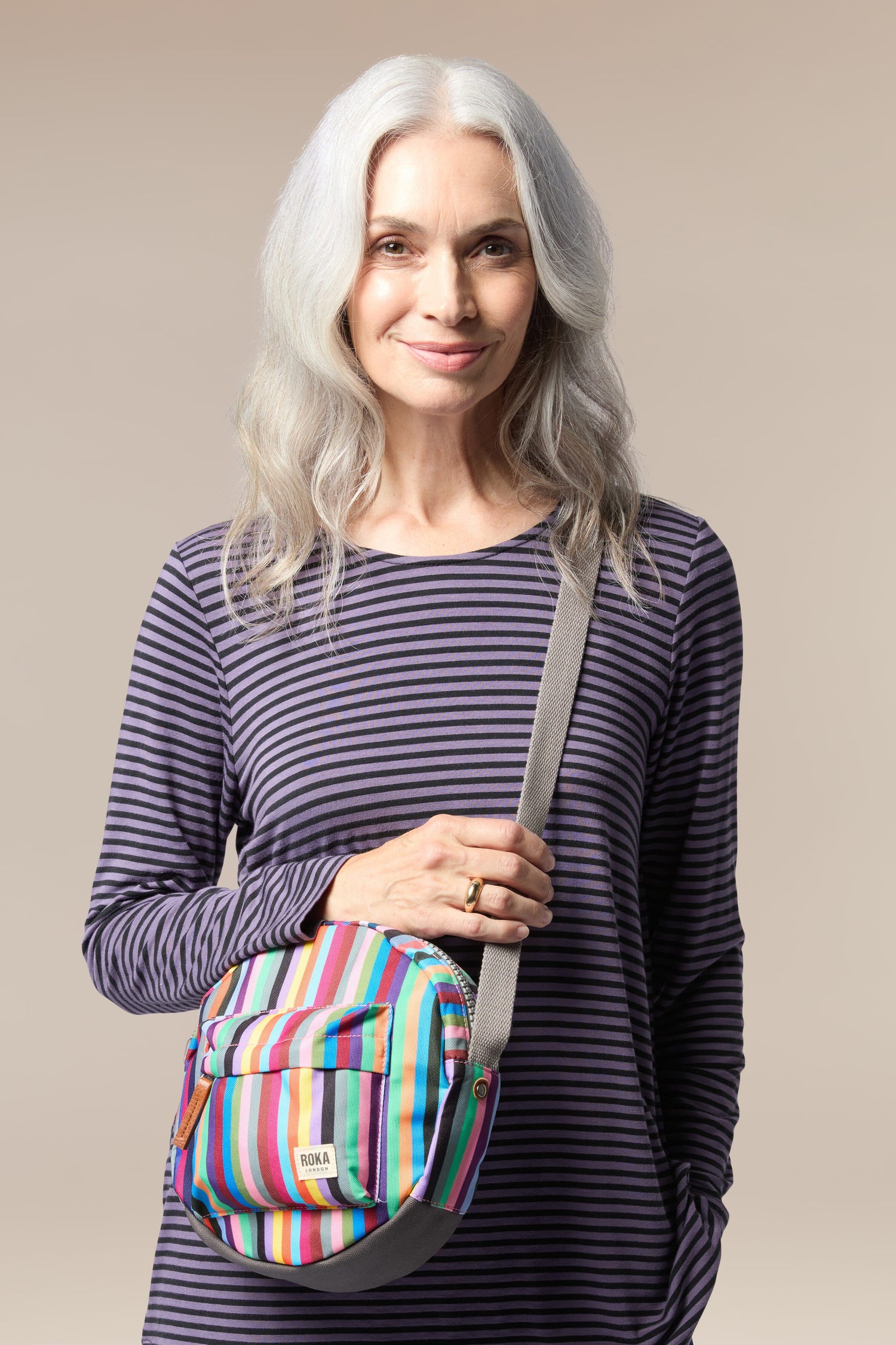 A woman holding a lightweight, colorful striped Recycled Canvas Paddington Bag.