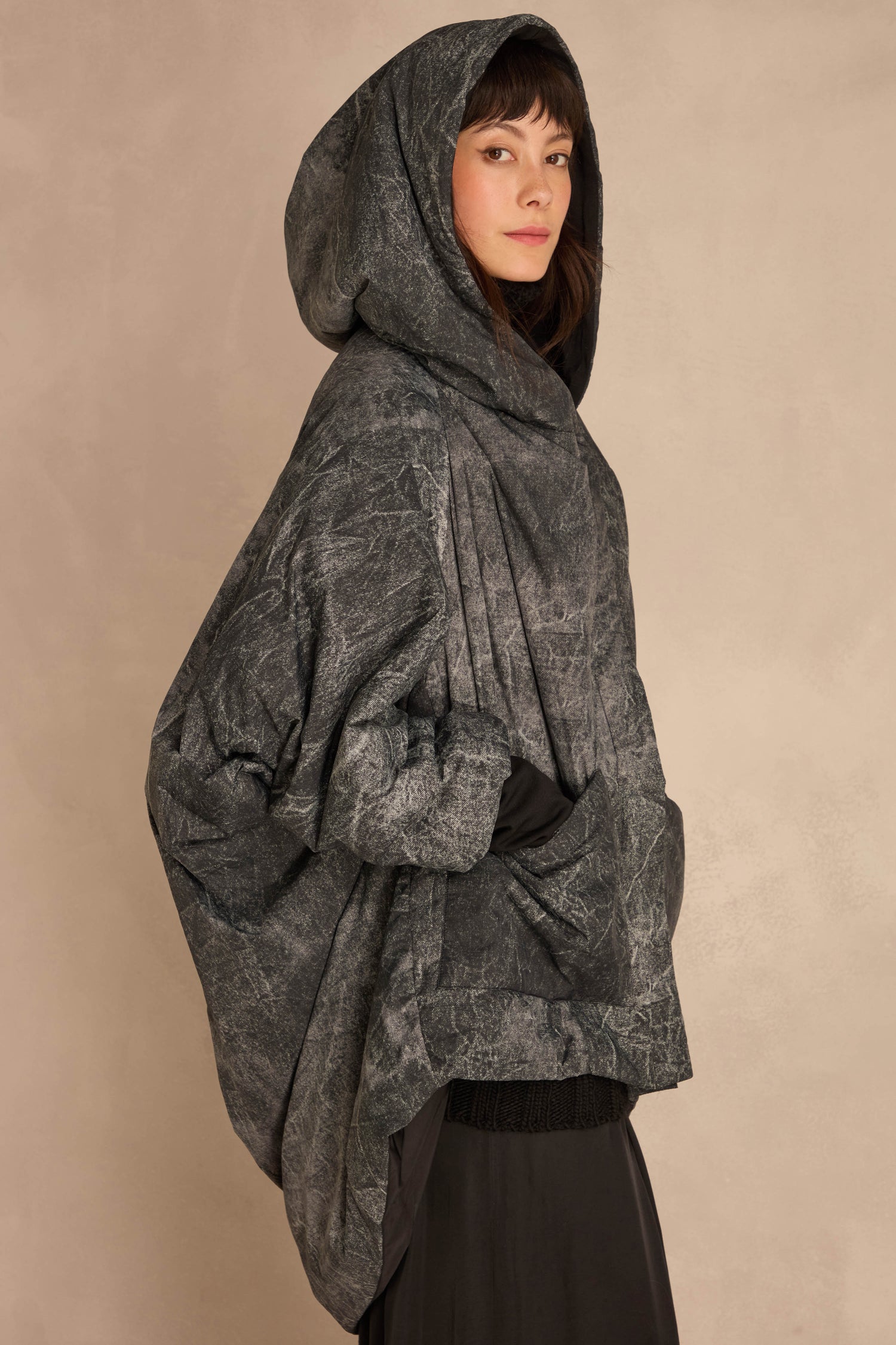 An Asymmetric Hooded Puffer Jacket in a textured grey pattern with an oversized fit and an asymmetric front closure.