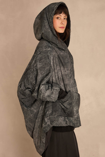 An Asymmetric Hooded Puffer Jacket in a textured grey pattern with an oversized fit and an asymmetric front closure.