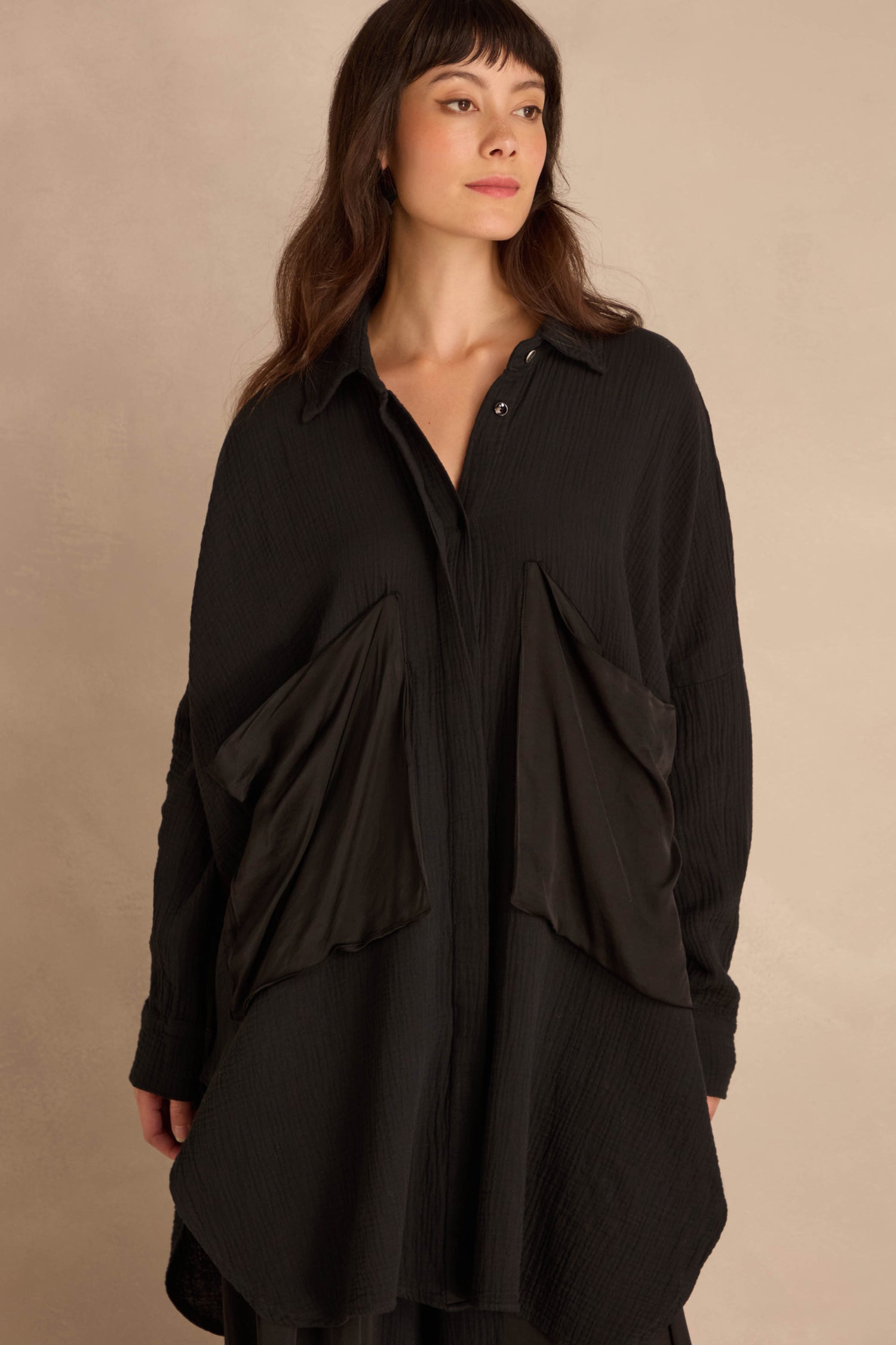 Model wearing a Black Pocket Satin Shirt in oversized, crinkled black cotton with two large, angular satin patch pockets.