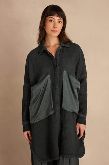 A model wears a dark green Petrol Pocket Satin Shirt featuring an oversized fit and two large, contrasting pockets on the front.