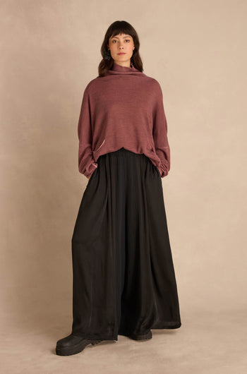 A person wearing a dusty rose mock-neck sweater and Black Wide Leg Panel Trousers.