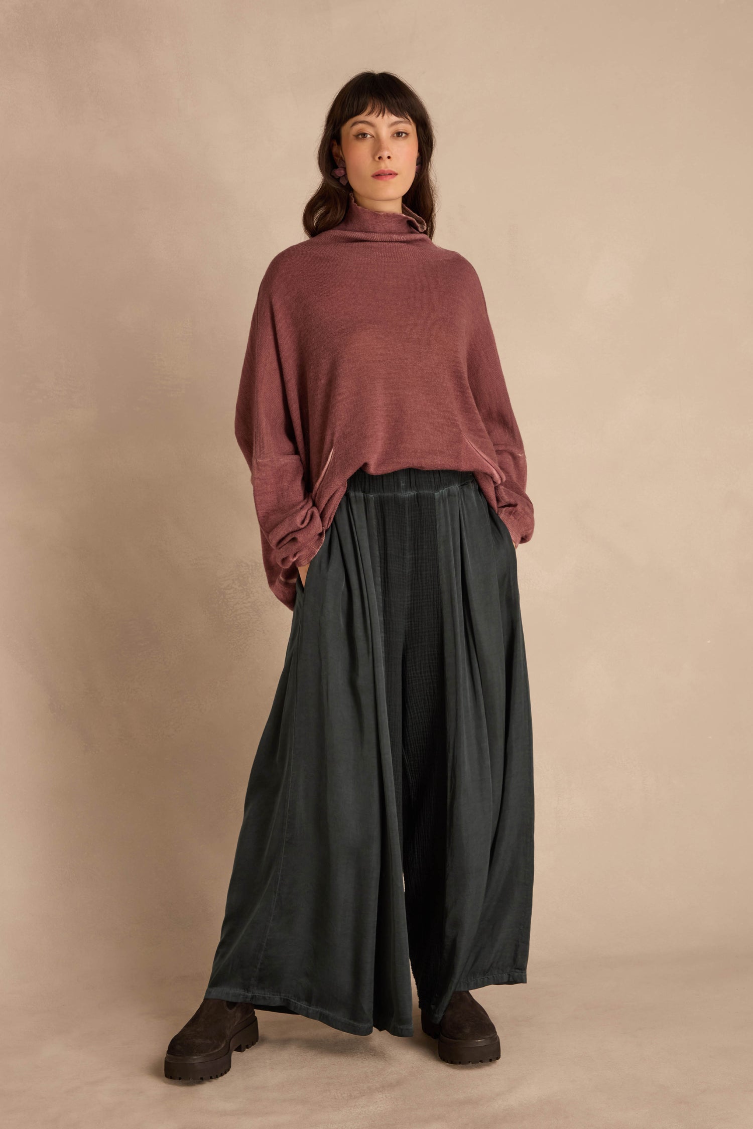 A model wears a maroon turtleneck sweater and Petrol Wide Leg Panel Trousers, which are dark, wide-leg cotton pants with a gathered waist.