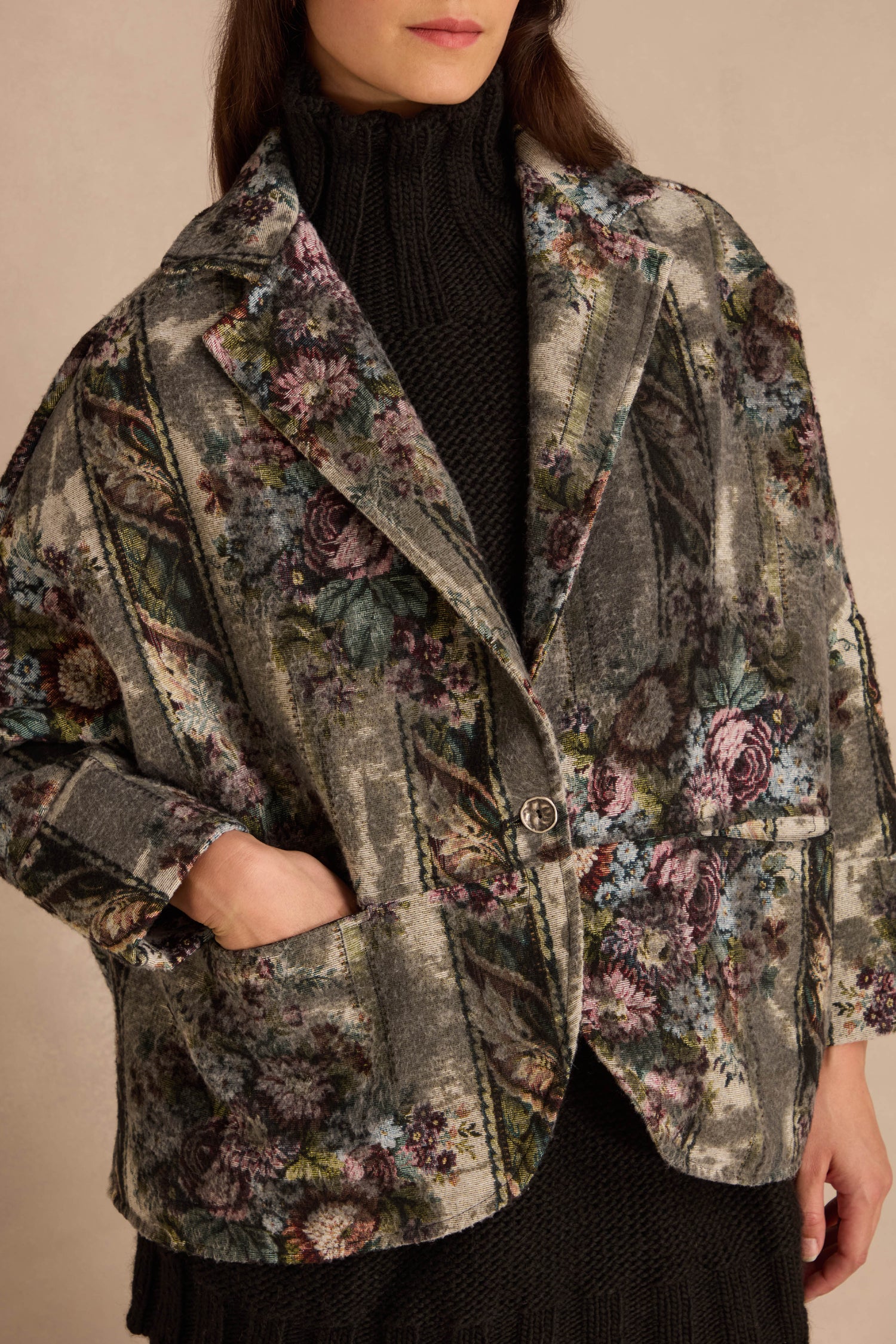 A person wears an oversized, floral Tapestry Jacket over a black ribbed sweater.