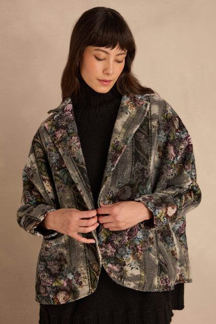 A person wears a grey floral Tapestry Jacket over a black turtleneck sweater.
