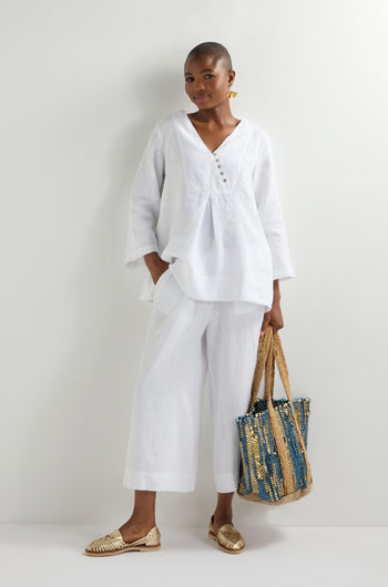 Dressed in a crisp white blouse and pants, the person holds a Blue Upcycled Leather Tote Bag, a testament to sustainable craftsmanship. They effortlessly stand against a plain background, embodying style with purpose.