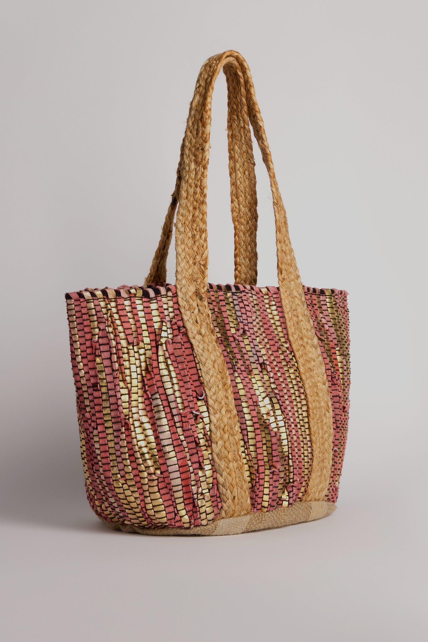 The Rose Upcycled Leather Tote Bag is handmade in India, boasting sustainable craftsmanship and a textured design with multicolored patterns, featuring thick braided handles.