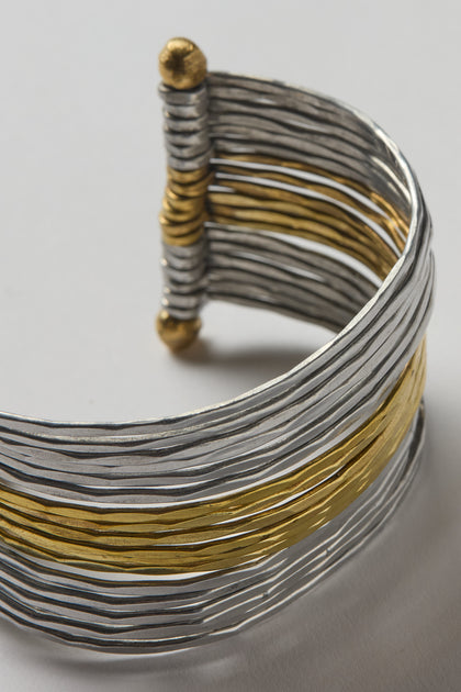 The Mixed Metal Cuff is a versatile statement bracelet with parallel silver and gold strands, finished with gold-toned round ends and a clasp.