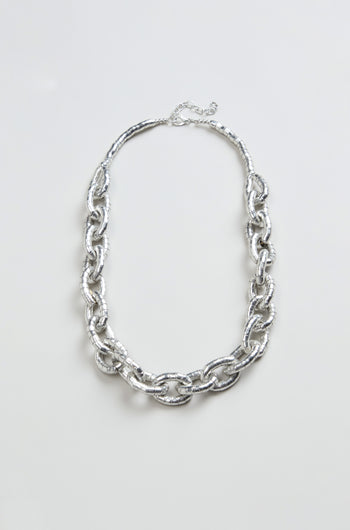 The Soft Loops Necklace, featuring large textured silver-toned oval links, is showcased on a plain light background.