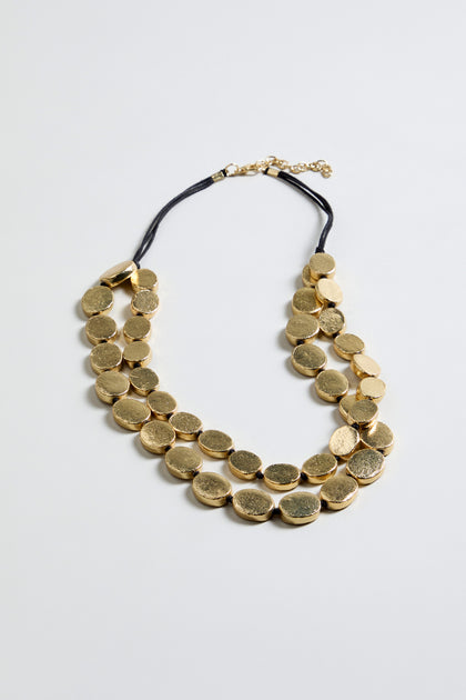 The Double Strand Oval Disc Necklace features two rows of gold-colored, textured oval discs on a black cord with an adjustable clasp, displayed against a plain light background.