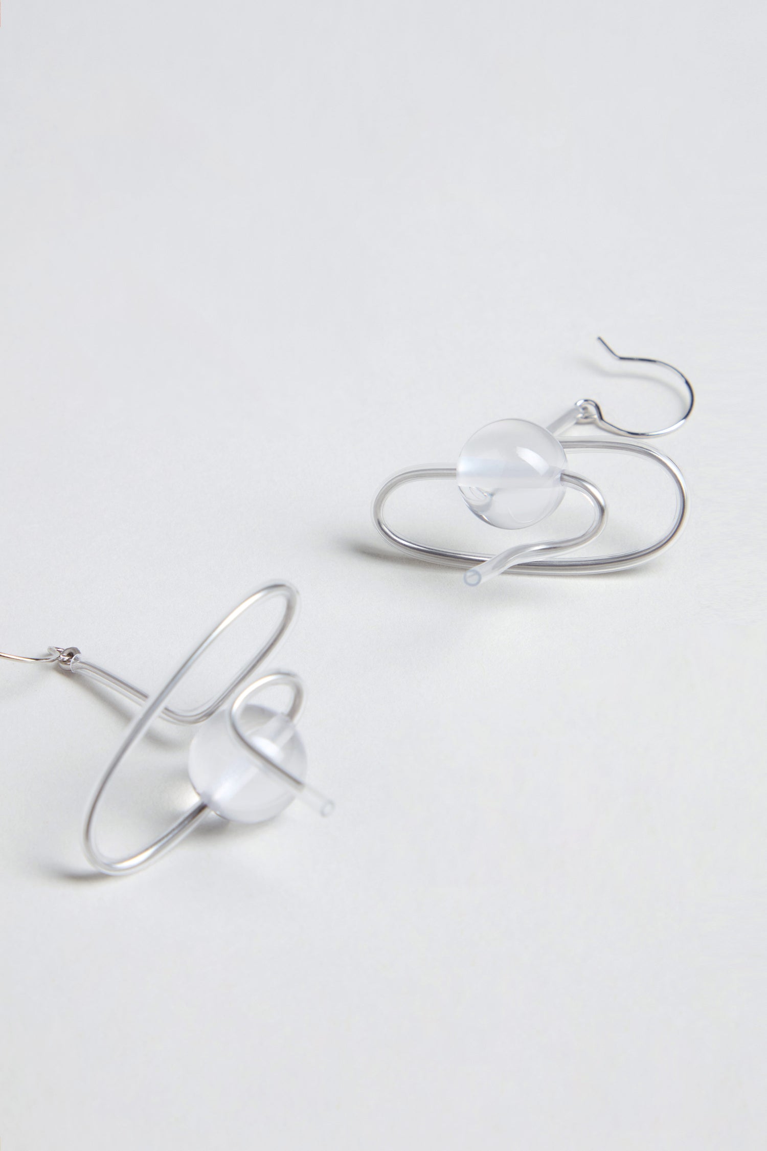 The Sketch Ball Earrings are handmade in Paris, featuring sculptural silver wire and clear spherical beads, shown on a plain white background.